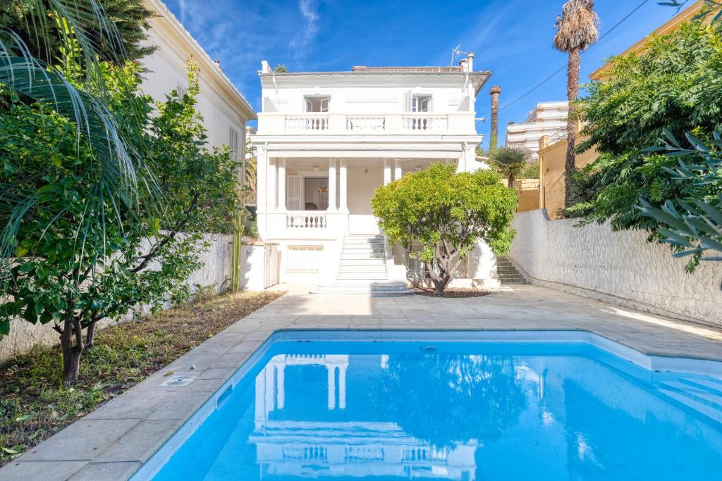 eine Villa mit einem Pool vor einem Haus in der Unterkunft Stylish Art Deco villa near the sea 4 Bdrs Pool and garage in Nizza