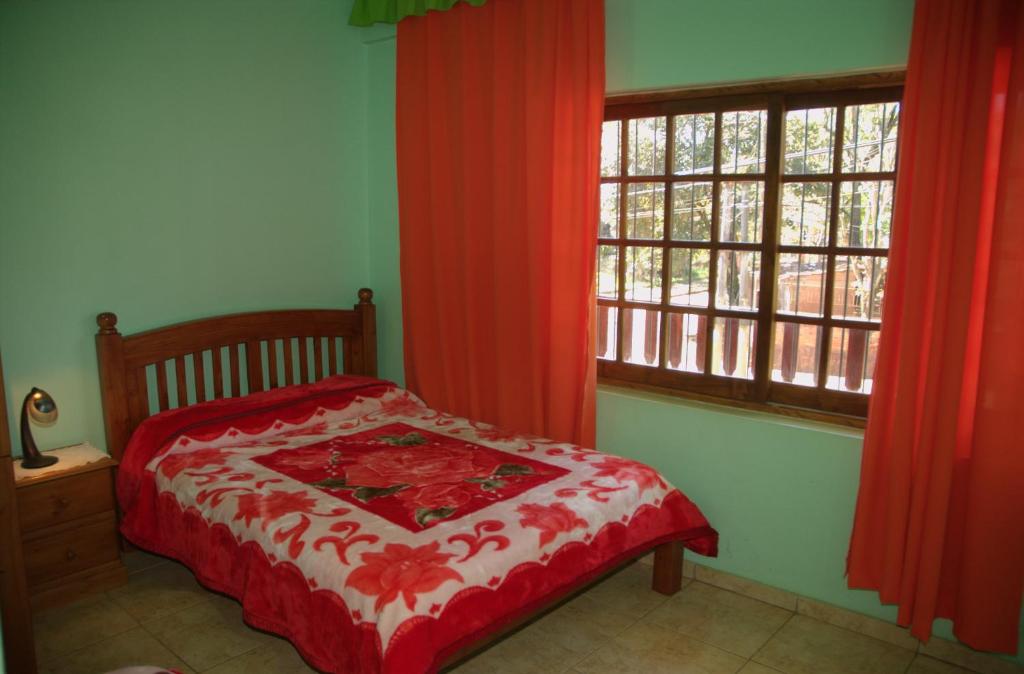 プエルトイグアスにあるHostel Peter Panのベッドルーム1室(ベッド1台付)、赤いカーテン付きの窓が備わります。