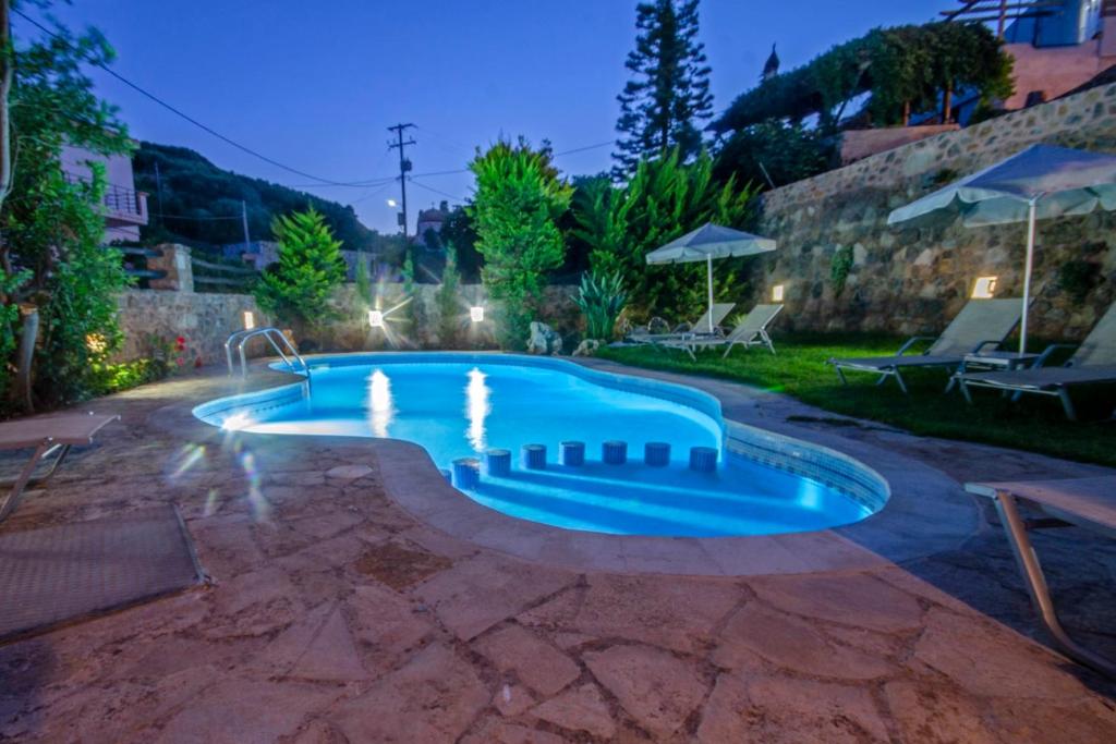 a swimming pool in a backyard at night at Aretaki villas in Astrátigos