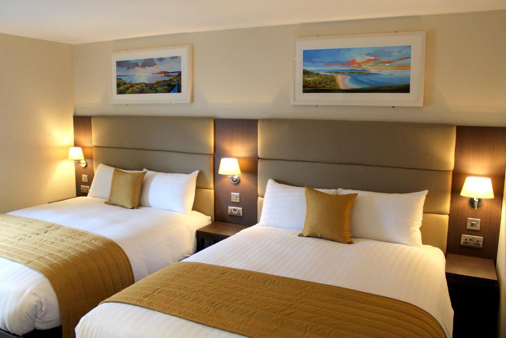 Habitación de hotel con 2 camas y 2 cuadros en la pared en Joyce's Carndonagh Inishowen en Carndonagh