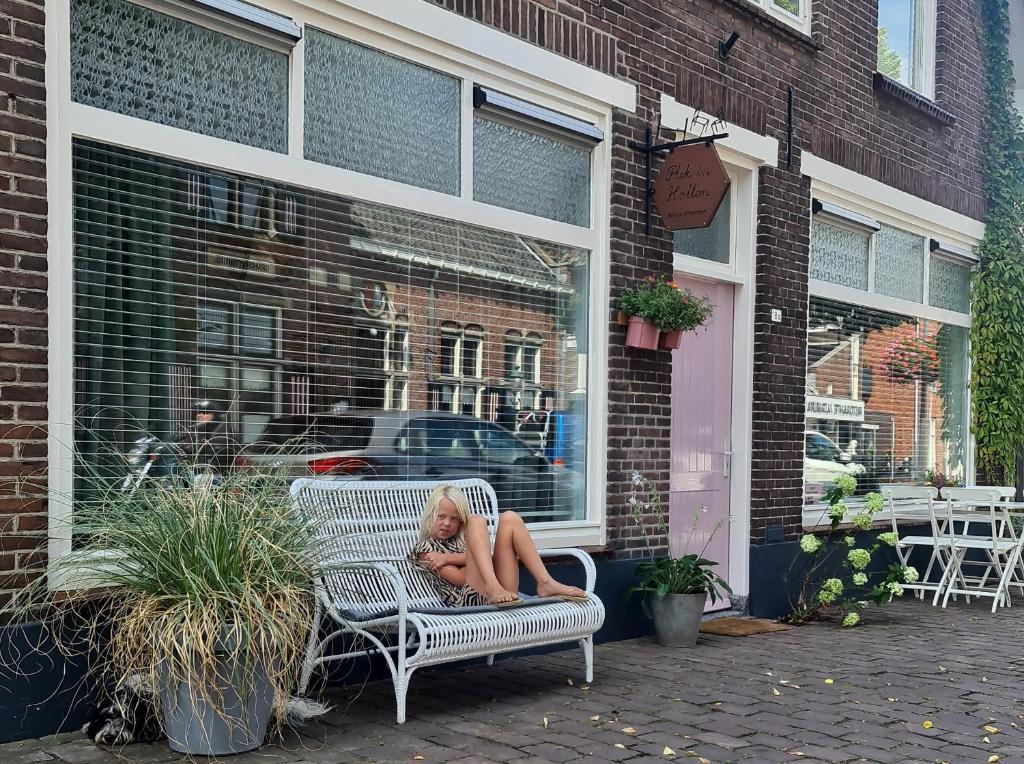 une femme assise sur un banc à l'extérieur d'un magasin dans l'établissement Appartement Plek in Holten, à Holten