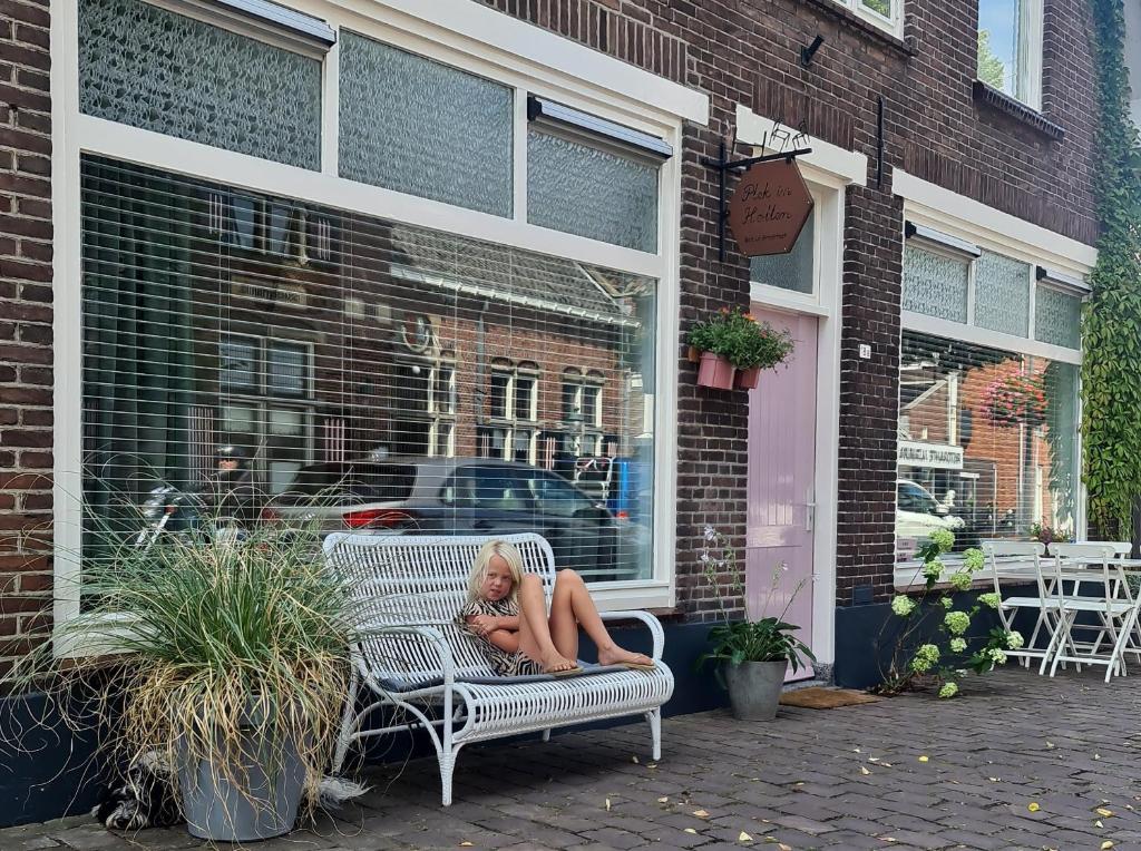 a woman sitting on a bench outside of a store at Appartement Plek in Holten in Holten