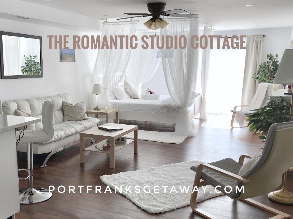 a white living room with a couch and a table at Romantic Studio Cottage in Lambton Shores