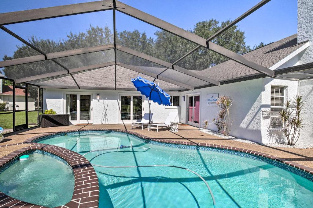a swimming pool with an umbrella and a house at Waterfront Rancher Retreat - Exotic Bird Haven in Valrico