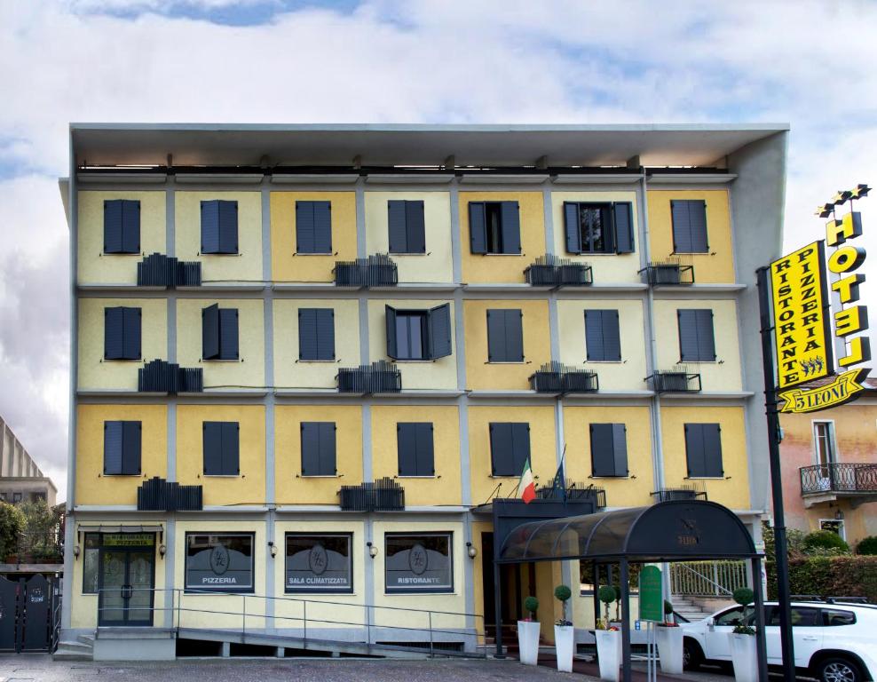 a large yellow building with a car parked in front of it at Hotel Ristorante Tre Leoni in Somma Lombardo