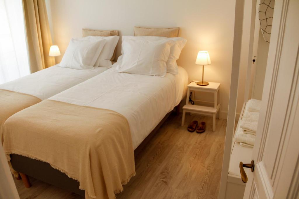 Caparica Downtown Apartment في كوستا دا كاباريكا: غرفة نوم بسرير كبير عليها شراشف ووسائد بيضاء