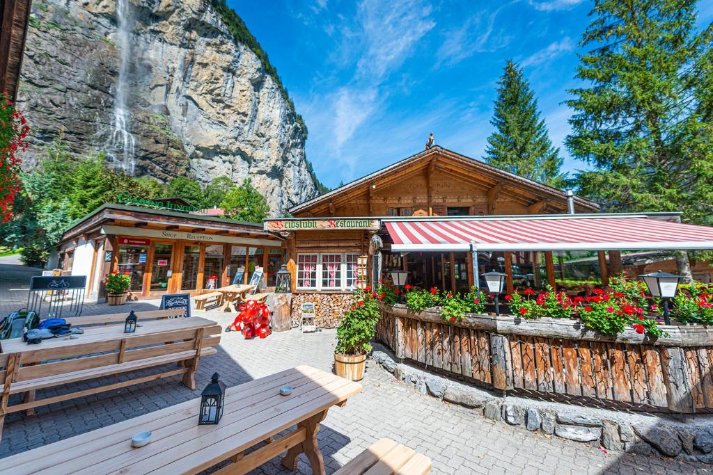 Un bâtiment avec des bancs et des fleurs devant lui dans l'établissement Camping Jungfrau, à Lauterbrunnen