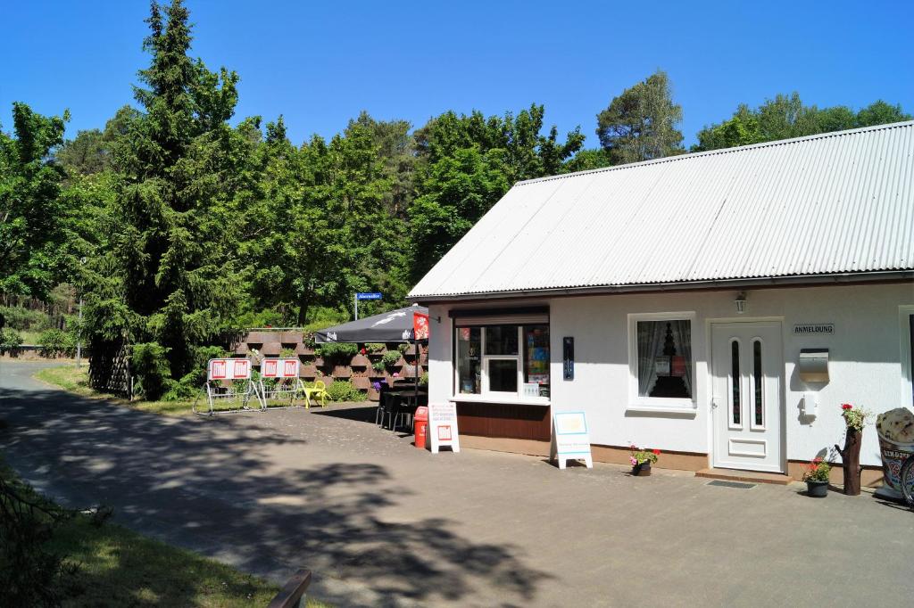 a white building with a table and chairs outside at Ferienhaussiedlung am Chossewitzer See in Friedland
