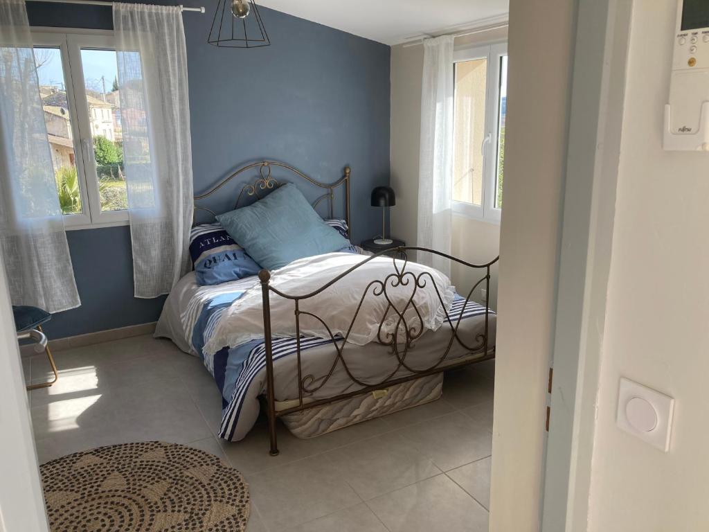 Un dormitorio con una cama con paredes y ventanas azules. en Sitio Nathalie et Jos, en Saint-Laurent-de-Carnols
