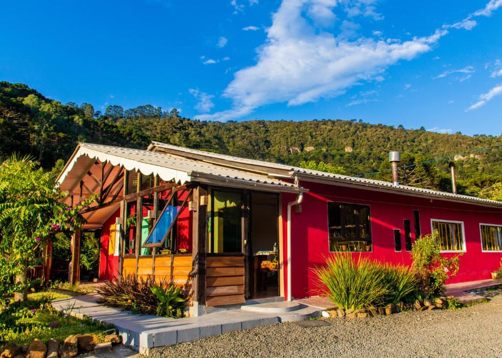 una casa roja con una montaña en el fondo en Hospedagem Rural Recanto do Riacho en Urubici