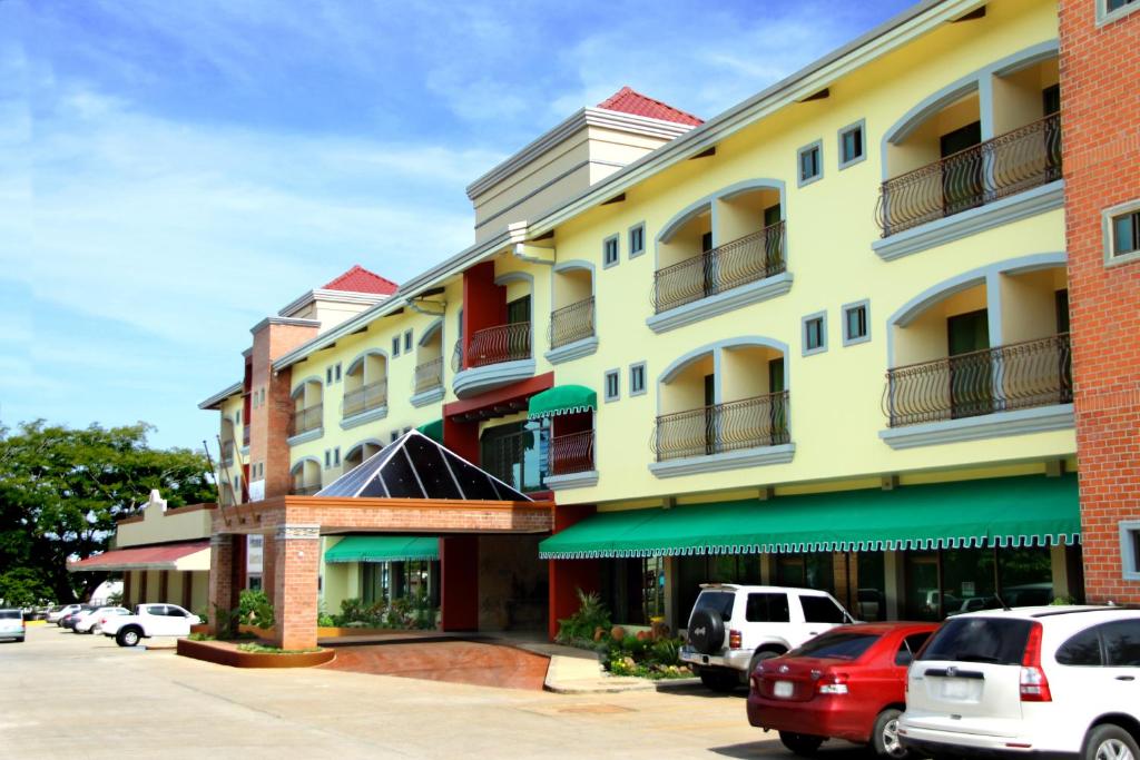 a yellow building with cars parked in a parking lot at Gran Hotel Azuero in Chitré