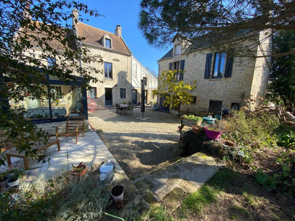 una casa con un patio con bancos delante en Le mas Normand en Ver-sur-Mer