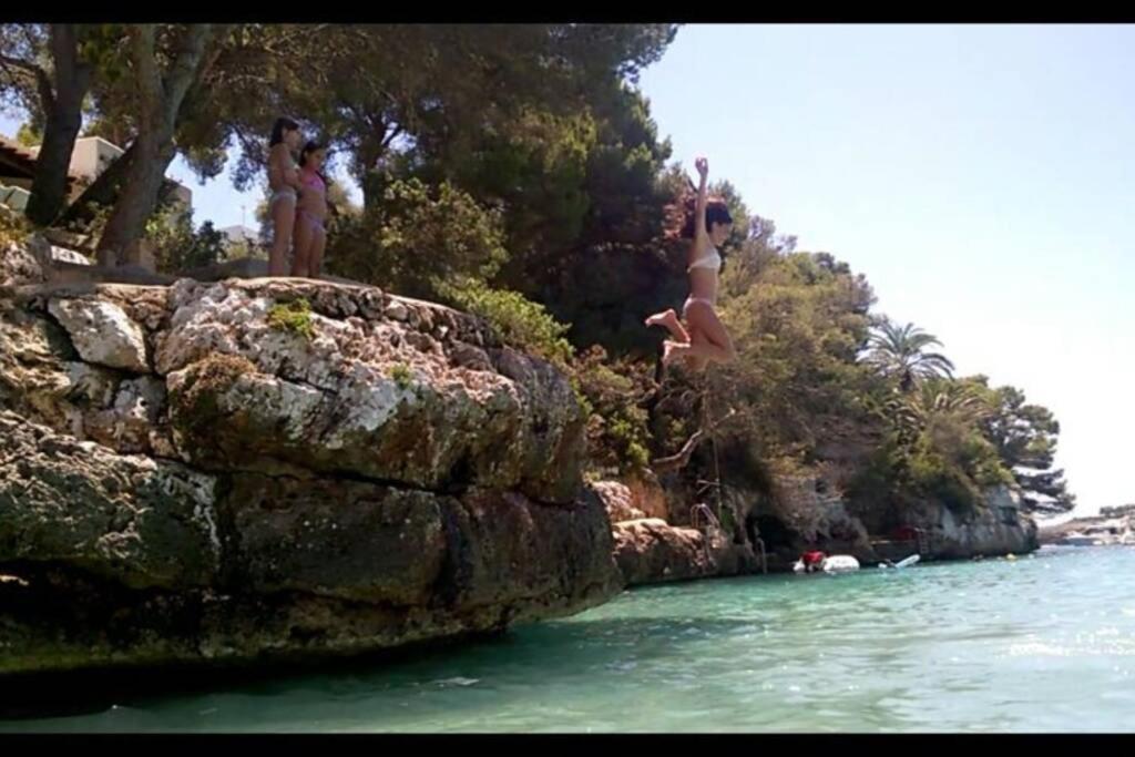 Eine Gruppe von Menschen springt von einer Klippe ins Wasser in der Unterkunft cala serena beach 6 in Cala Serena