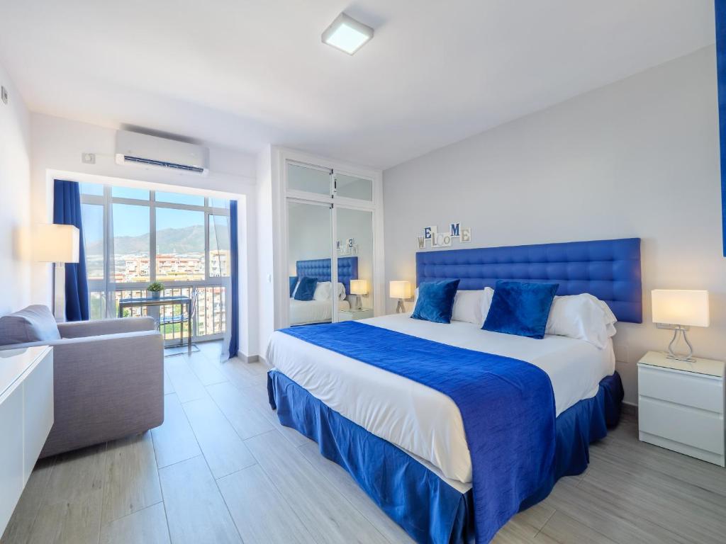 ベナルマデナにあるHoneymoon Apartmentsの青いベッドとソファ付きの広いベッドルーム1室が備わります。