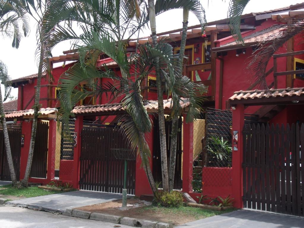 um edifício vermelho com palmeiras em frente em Chalés Ubatubaloft em Ubatuba