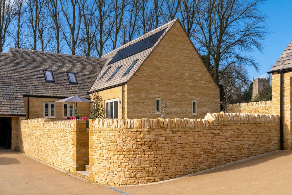 a brick wall with a house behind it at Maple House in Chipping Campden