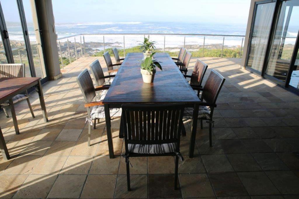 a table with chairs and a potted plant on a balcony at Whalesong Villa in Hermanus