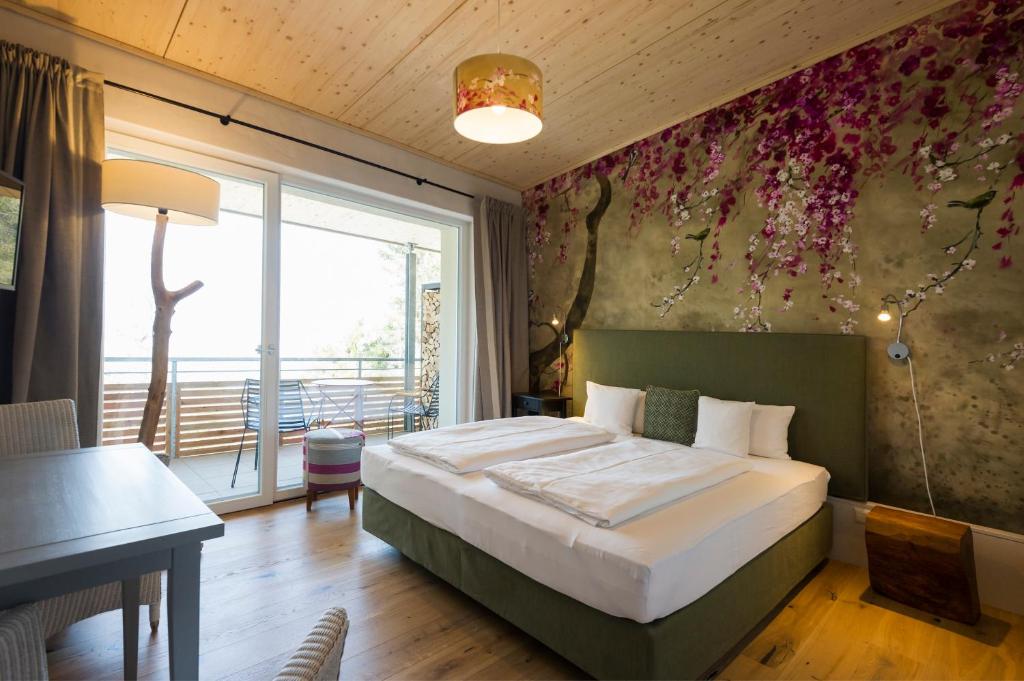 Schlafzimmer mit einem Bett, einem Tisch und einem Fenster in der Unterkunft Berghaus Freiburg - Appartement Hotel auf dem Schauinsland in Oberried