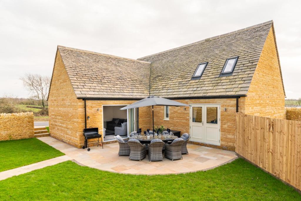 a house with a patio with a table and an umbrella at Rowan House in Chipping Campden