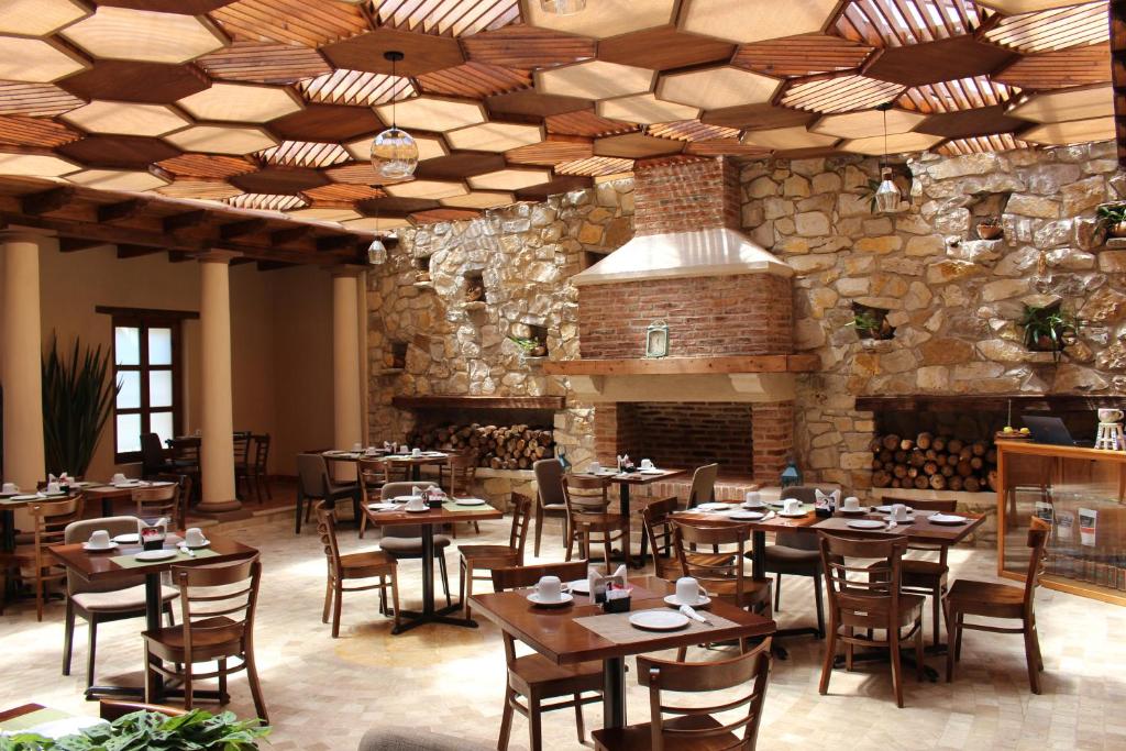 a restaurant with wooden tables and chairs and a stone wall at La Estancia in San Cristóbal de Las Casas