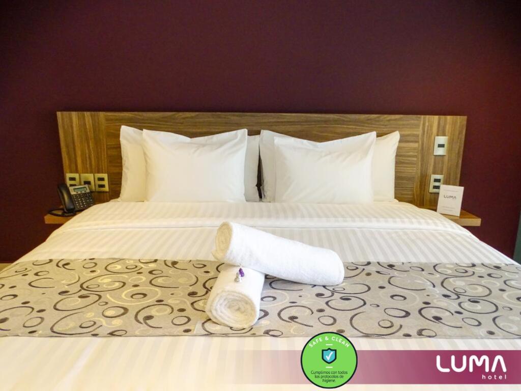 a hotel bed with two rolls of towels on it at Hotel Luma by Kavia in Cancún