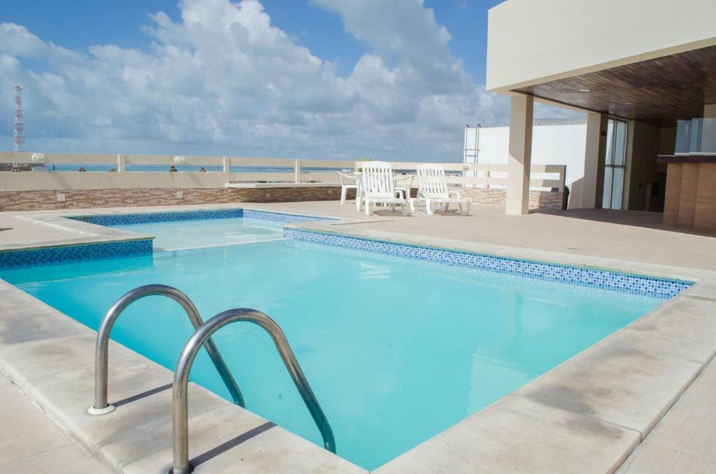 uma grande piscina com cadeiras e praia em Aram Ouro Branco Hotel em Maceió