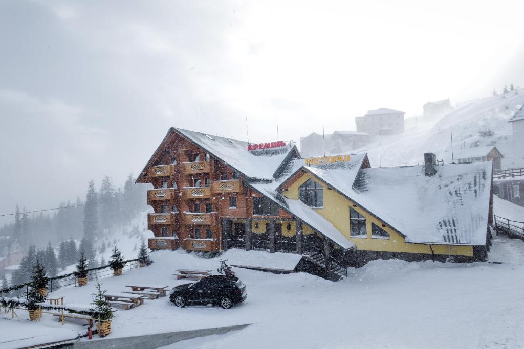 um edifício coberto de neve com uma mota de neve à sua frente em КРЕМІНЬ em Dragobrat