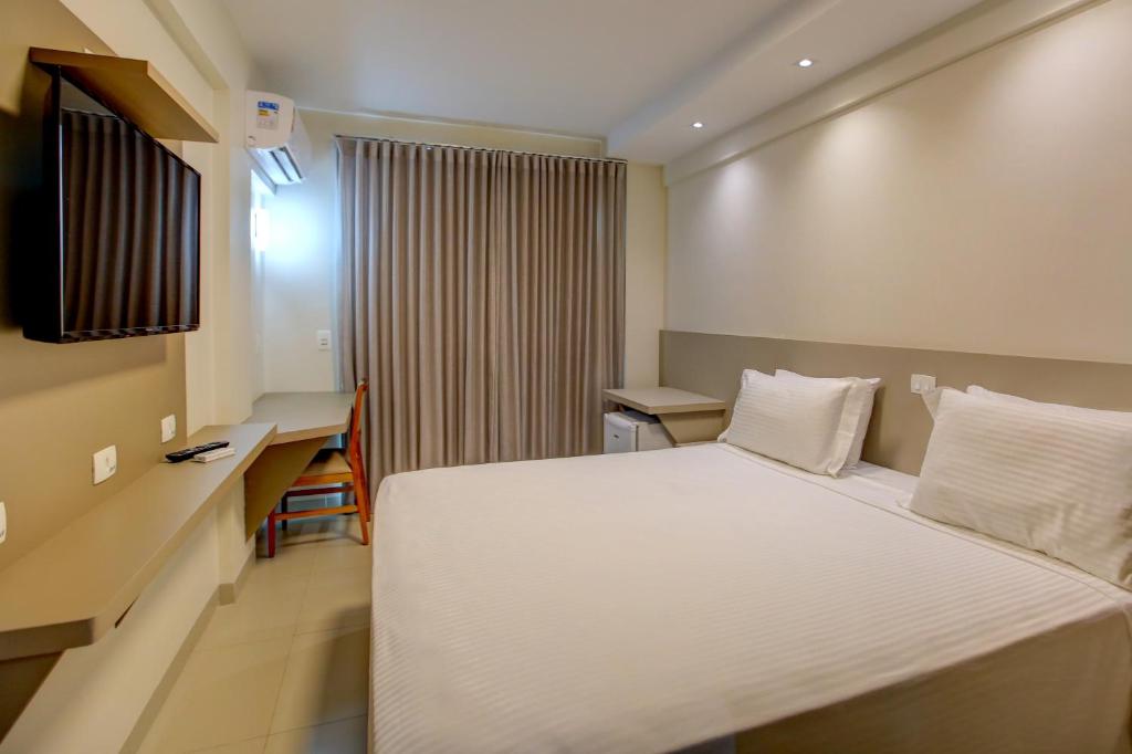 a hotel room with a bed and a desk at Novares Hotel in Goiânia