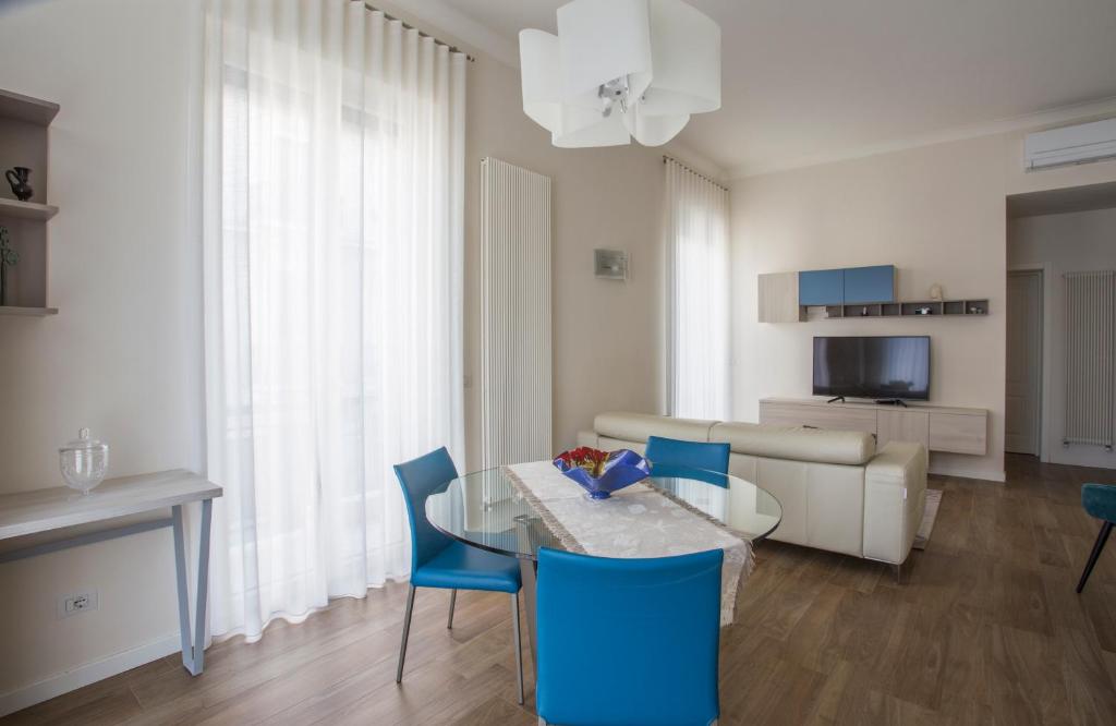 a living room with a glass table and blue chairs at La Casa di Nausicaa : il piacere dell'ospitalità in Reggio Calabria