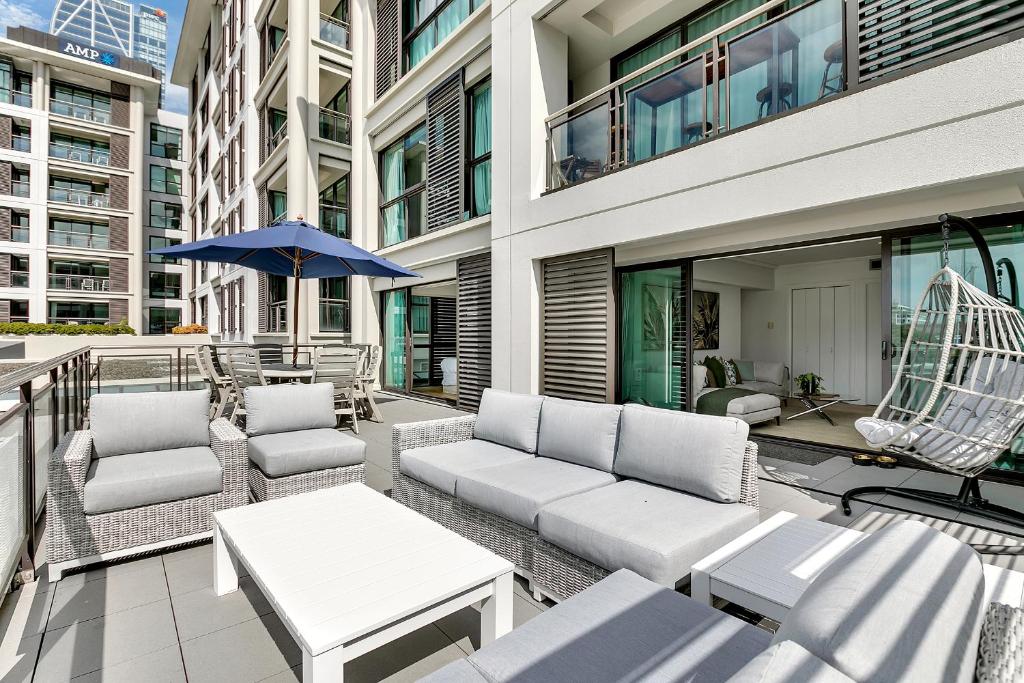 a patio with a couch and chairs and an umbrella at Ultimate outdoor-living Urban Getaway! 1 Carpark in Auckland