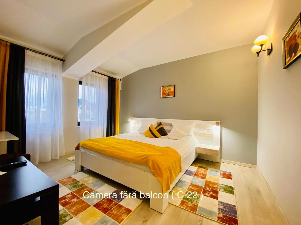 a bedroom with a bed with a yellow blanket at Pensiunea Camena in Piatra Neamţ