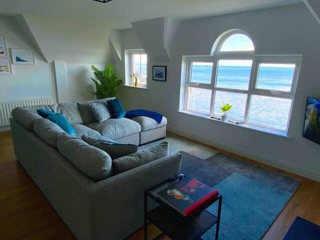 a living room with a couch and a large window at Island Dhu View - Seaside Penthouse in Portrush in Portrush
