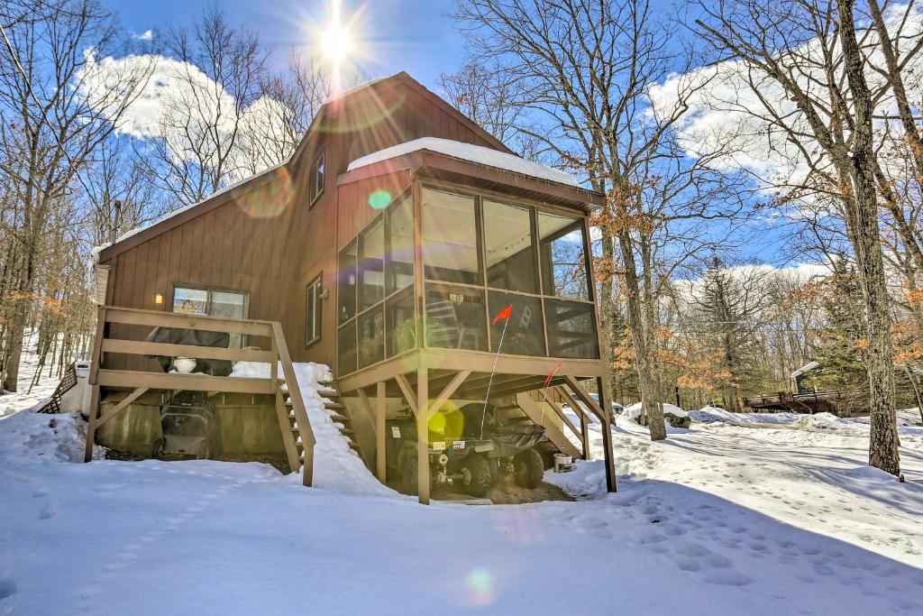 a small cabin in the snow with the sun behind it at Pet-Friendly Poconos Getaway with Resort Perks! in Lackawaxen