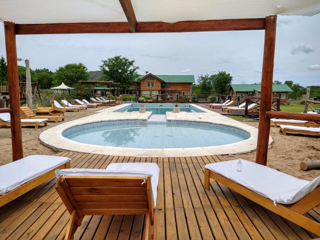 una piscina en una terraza de madera con tumbonas en Cabañas del Espinillo en Villa General Belgrano