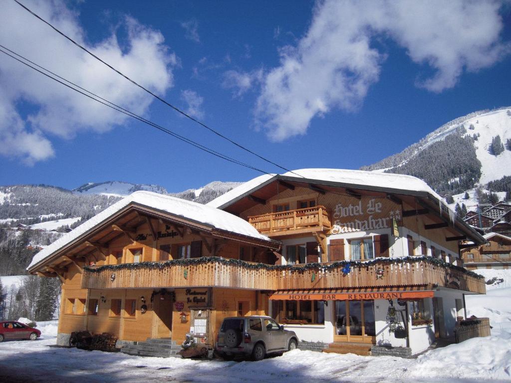 ein großes Holzgebäude mit Schnee darauf in der Unterkunft Hôtel Le Kandahar in Châtel