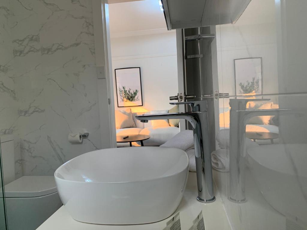 een witte badkamer met een wastafel en een toilet bij Garden Apartment - Short Walk to Harbour Bridge in Sydney