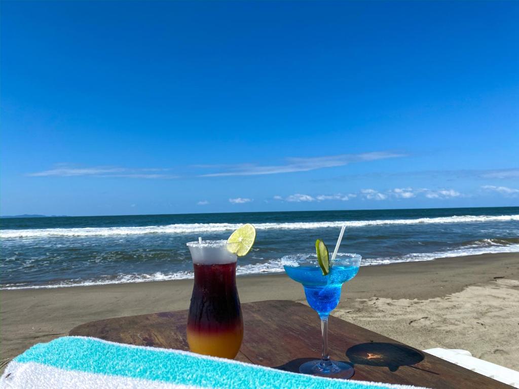 a table with a drink and two glasses on the beach at La Ensenada Beach Resort in Tela
