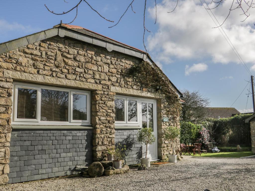 a stone house with a garage at Honeysuckle Cottage in Helston