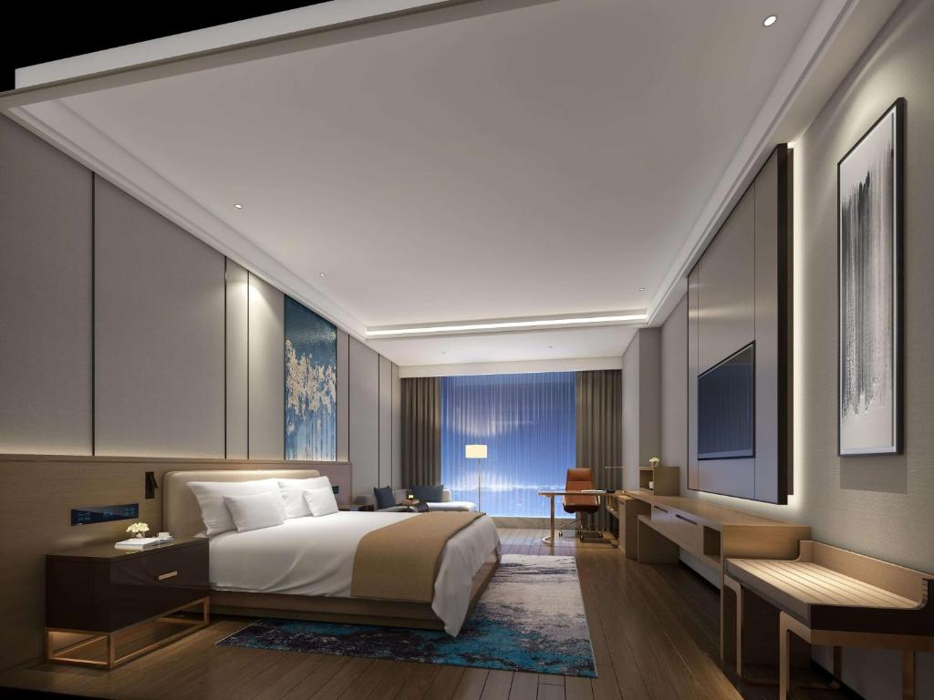 長沙市にあるWyndham Changsha Southのベッドとデスクが備わるホテルルームです。