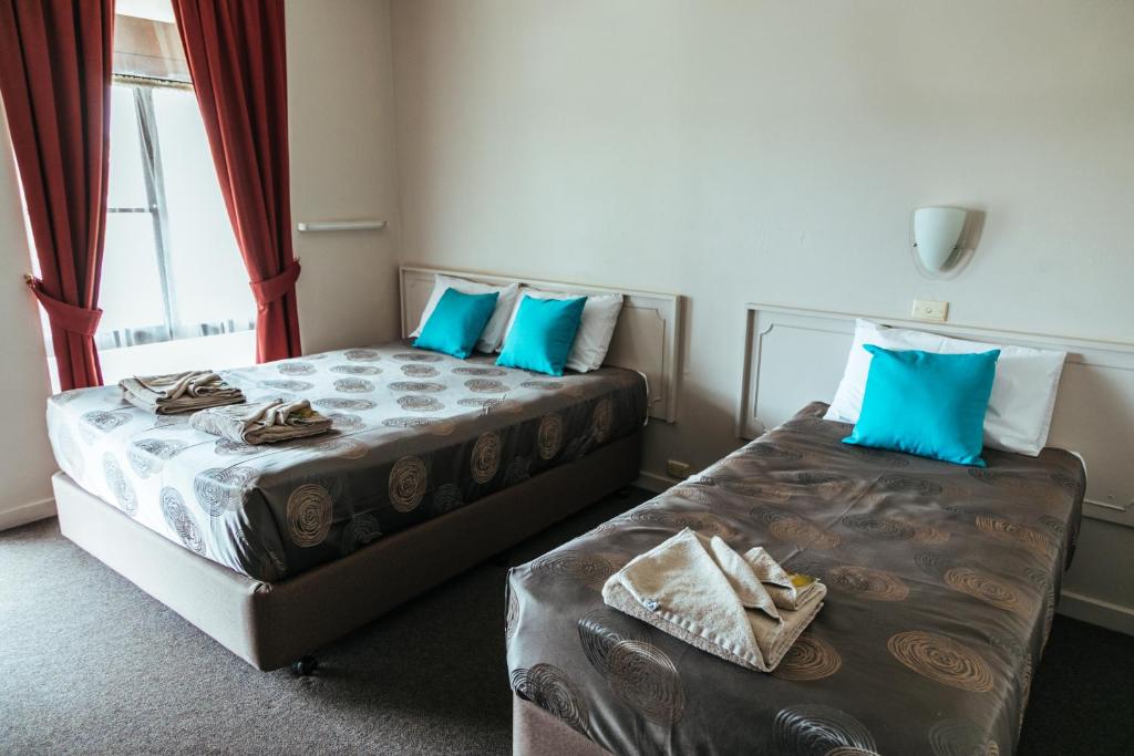 two beds in a room with blue pillows at The Argent Motel in Broken Hill