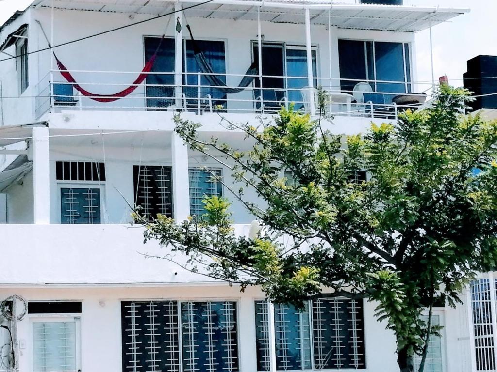 un edificio blanco con un árbol delante en Aparta Suites Romance de Verano, en Santa Marta