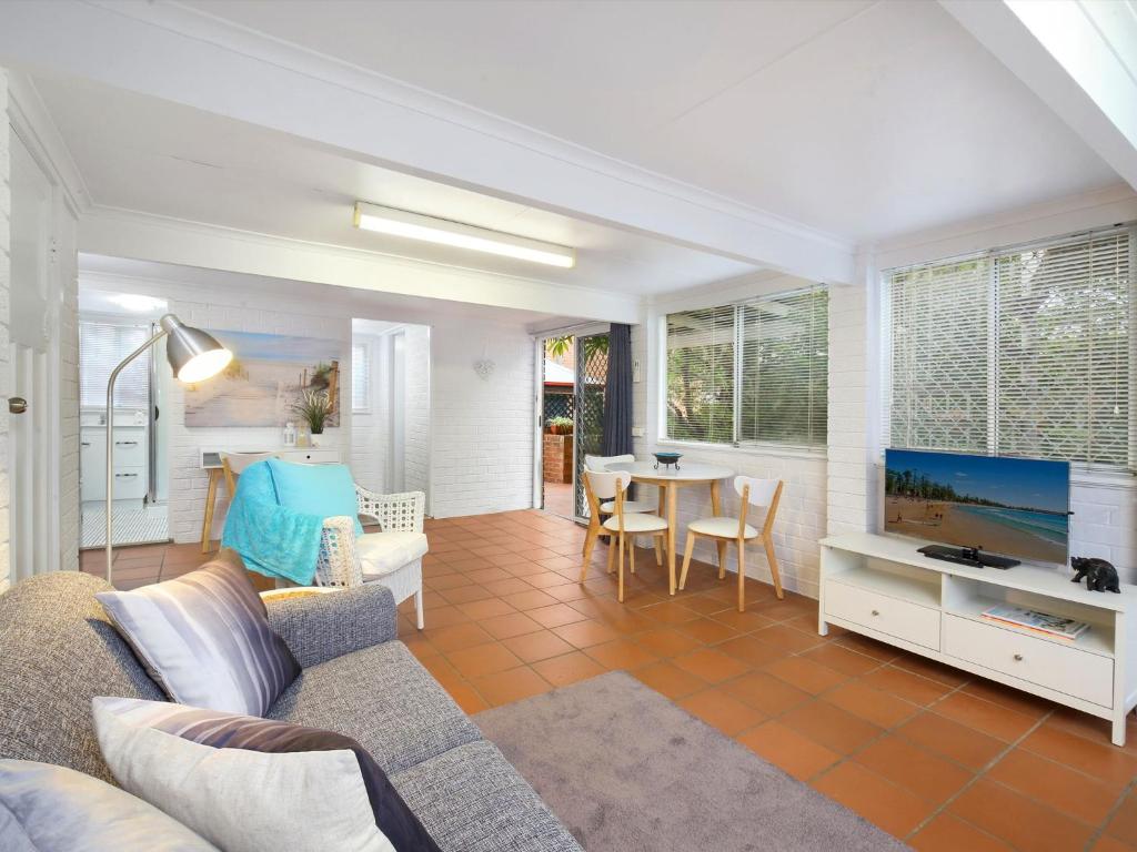 a living room with a couch and a tv and a table at Comfy Studio with Idyllic Yard in Great Location in Terrigal