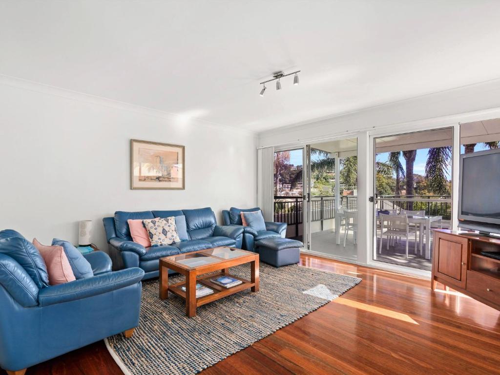 a living room with a blue couch and a tv at Spacious Beachside Townhouse with Large Balcony in Terrigal