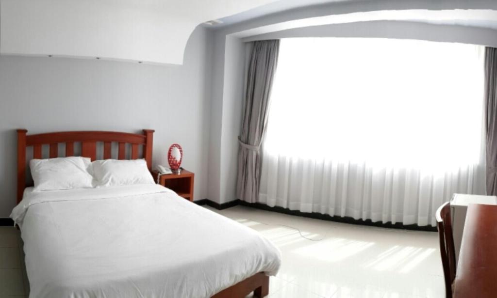 um quarto com uma cama e uma grande janela em DoDo Guesthouse em Phnom Penh