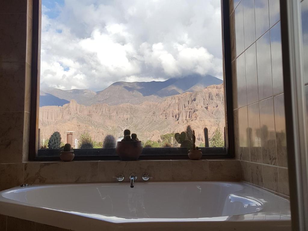 a bath tub with a window with a view of the mountains at La Quebrada Enigmática. Arte, mística e historia in Tilcara