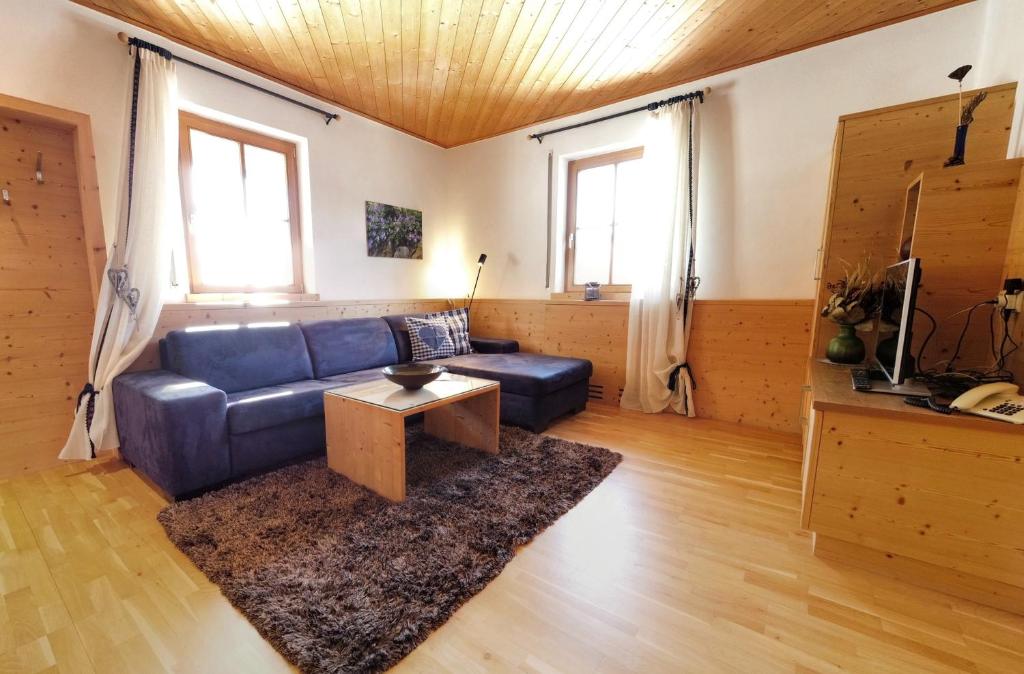 een woonkamer met een blauwe bank en een tafel bij Appartements Grumserhof in Merano