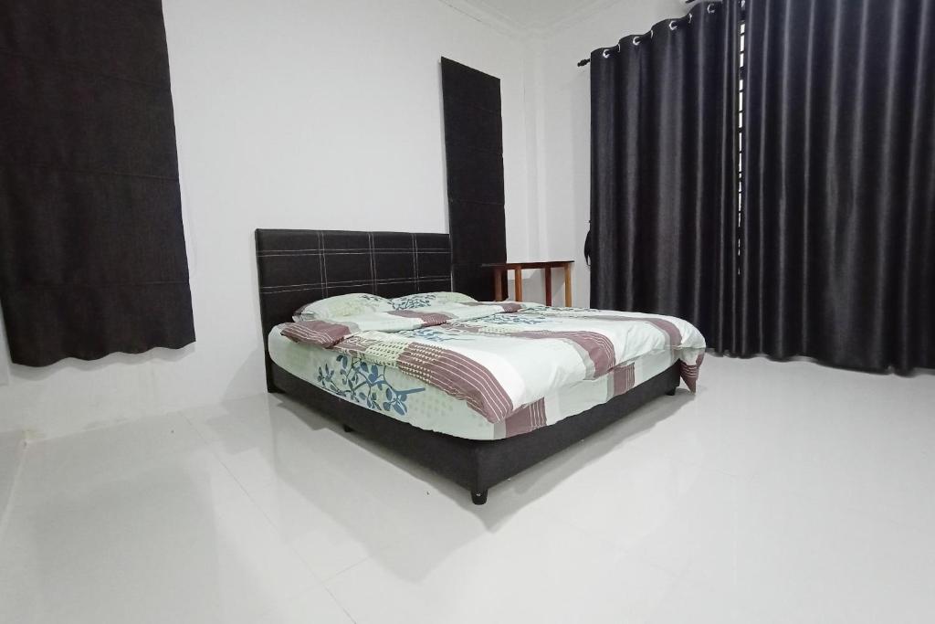 a bed in a room with black curtains at OYO Home 90203 Emma Sukma Homestay in Kuching