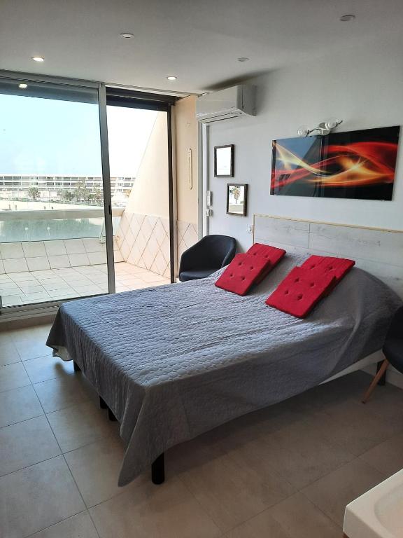 une chambre avec un lit avec deux oreillers rouges dessus dans l'établissement Naturiste Cap d'Agde Héliopolis D 11, au Cap d'Agde