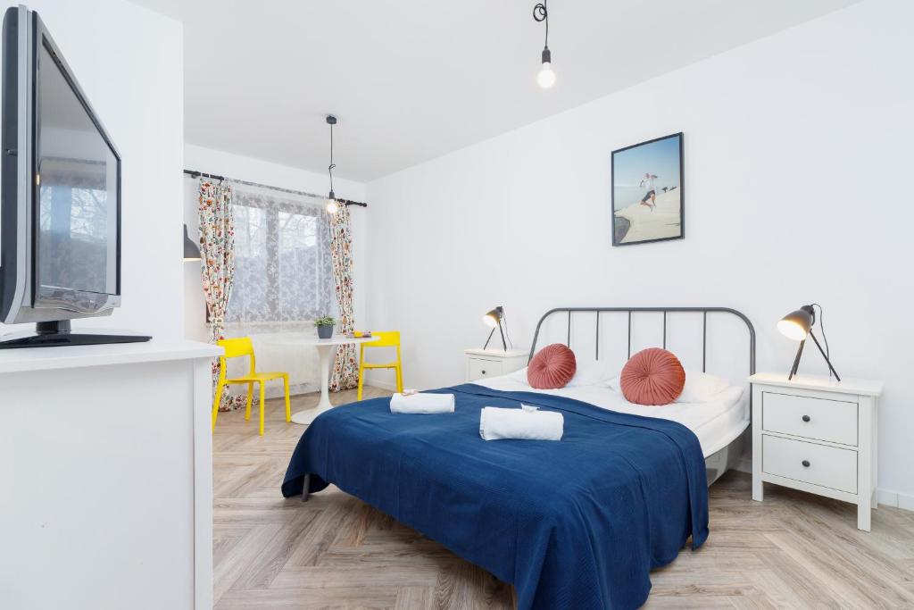 a bedroom with a bed with a blue blanket and a tv at Premium Apartment Ludwinowska Kraków by Renters in Kraków