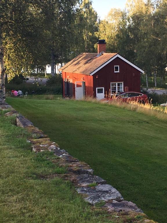 une grange rouge assise au-dessus d'un champ verdoyant et luxuriant dans l'établissement Trädgårdsstugan på Malingsbo herrgård, à Malingsbo